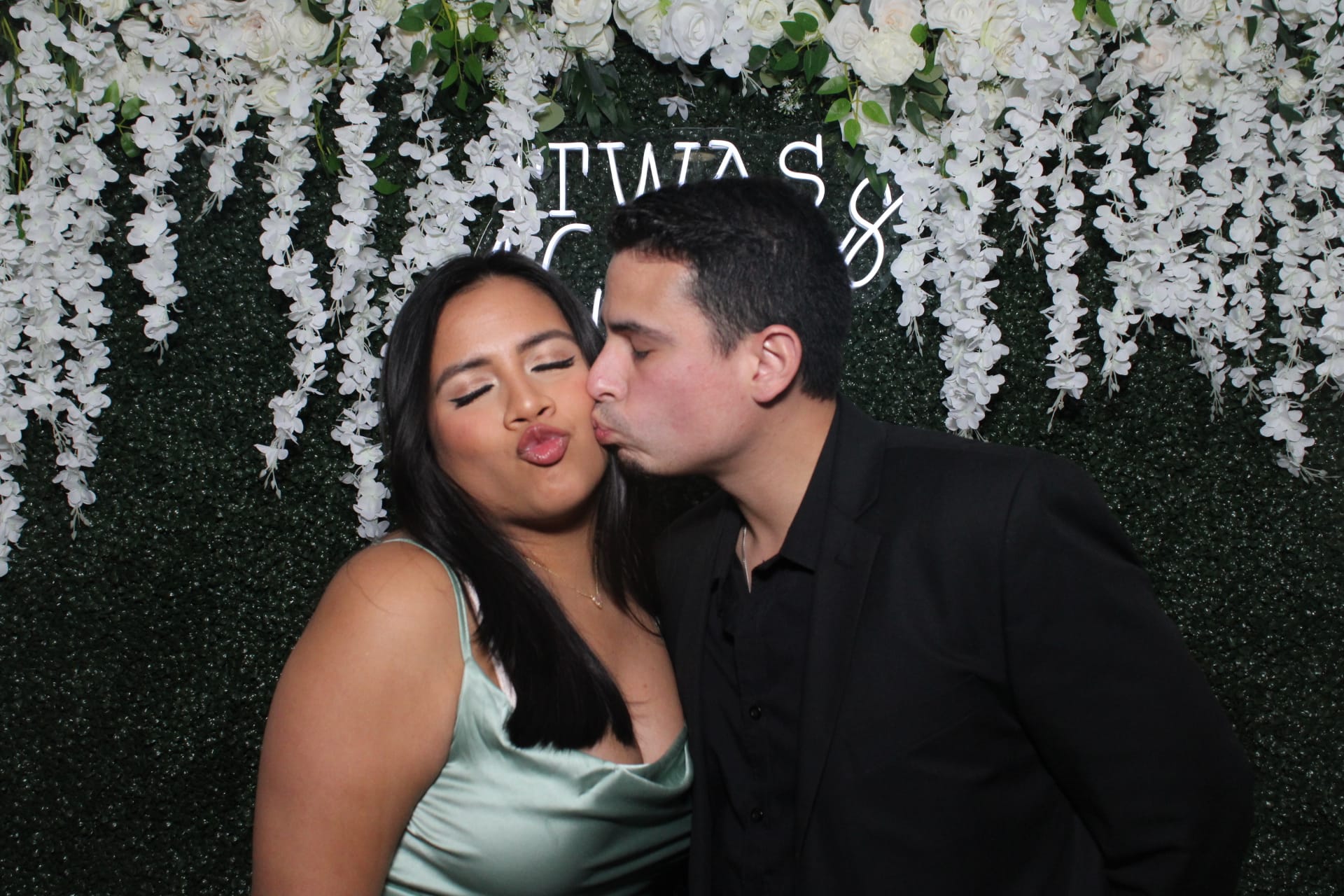 Couple posing in front of a lush floral wall